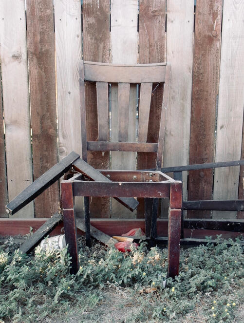 Broken chair. A broken wooden chair against an old wooden fence. California 2026. Photography by Mike Hamar.